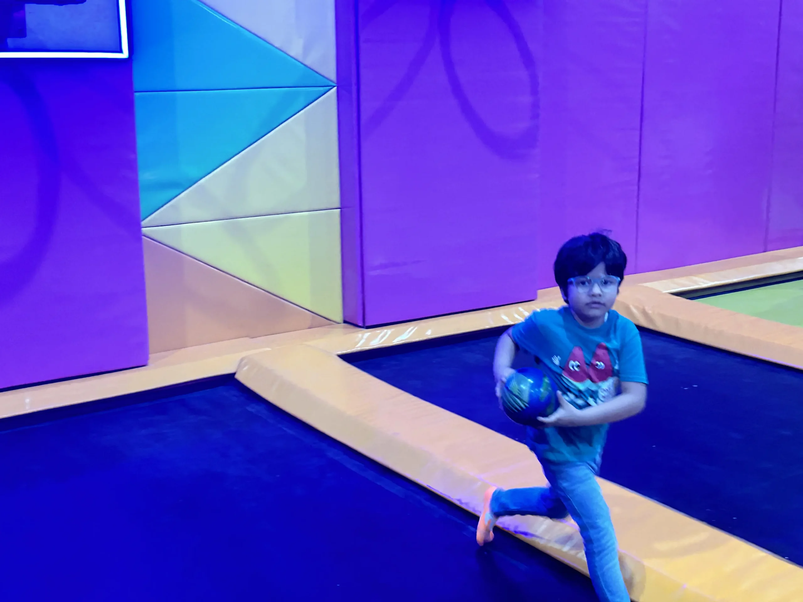 a boy playing on trampoline with ball